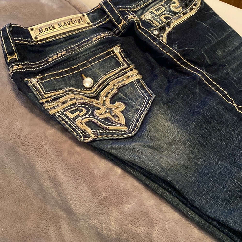These are Rock Revival jeans. Dark denim, with beige trimming.